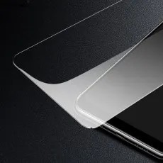 Close-up of a clear screen protector being applied to a smartphone on a black surface.