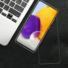 A Samsung Galaxy A72 phone with a screen protector next to a laptop