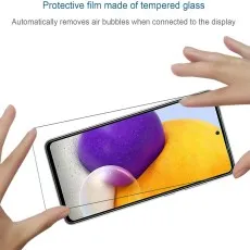 Hands applying a tempered glass screen protector to a Samsung Galaxy phone