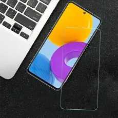 Screen protector next to a Samsung Galaxy M52 5G on a dark surface with a keyboard corner