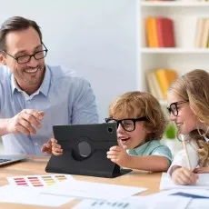 Samsung Galaxy Tab A9 Plus 11-Inch in a black 360° rotating leather case being used on a desk in a home or office setting with people working together