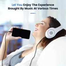 Person relaxing on a couch, listening to music with over-ear headphones connected to an iPhone using the black aux cable
