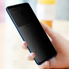 A hand holding a smartphone with a privacy screen protector, making the screen appear dark