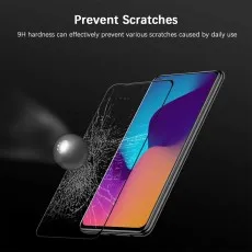 A smartphone with a colorful display lies next to a shattered screen protector and a metallic sphere