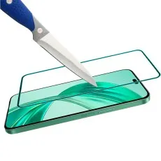 A knife tip touches a phone screen protector on a green smartphone, showing durability