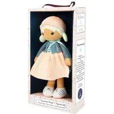 A soft, blonde-haired Kaloo doll with a pink hat, blue cardigan, and peach-colored dress is displayed inside a decorative gift box.