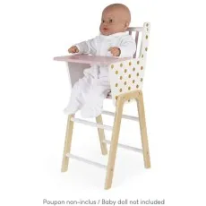 A Janod doll high chair with a gold polka dot pattern and a pink tray, with a baby doll sitting in it.