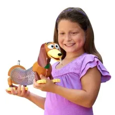 A smiling girl holds the Toy Story Slinky Dog pull toy..