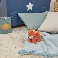 A child's room with a fluffy fox toy, a blue star wall decoration, and pillows.