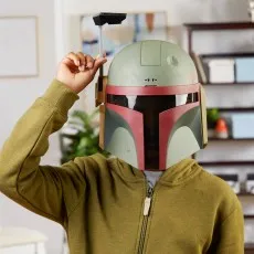 A person wearing a green hoodie and a Boba Fett helmet holds up the rangefinder on the side of the mask.