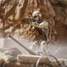 A G.I. Joe Action Soldier figure in a helmet and camouflage, kneeling and aiming a rifle.