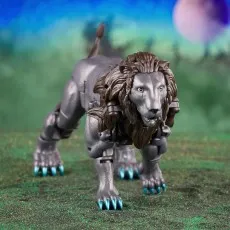 A Leo Prime Transformer toy in its lion form, with metallic fur and blue claws, posed on a grassy field