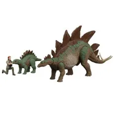 A person kneels next to a small toy stegosaurus, while a much larger version of the same dinosaur stands nearby.