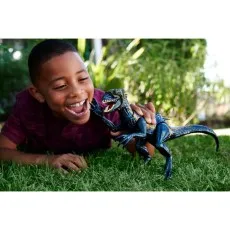 A happy child on the lawn playing with a black and gold Indoraptor dinosaur toy.