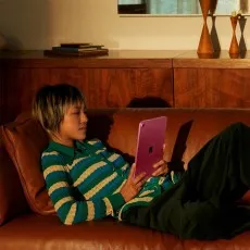 Person relaxing on a sofa using a Pink iPad in a cozy living room setting