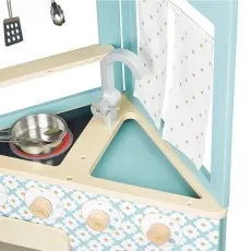 A close-up of a toy kitchen showing the sink, a frying pan on the stove, and a white curtain with stars.