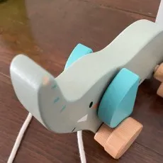 A close-up of a well-loved wooden elephant pull toy with some small scuff marks on its nose