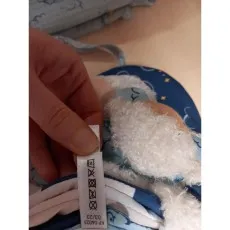 A close-up of a hand holding the care instructions label on a baby's plush toy.