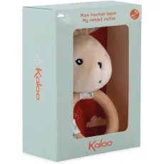 A close-up of a Kaloo plush rabbit rattle in its box, with a wooden ring