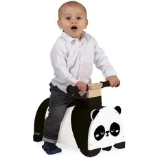A baby boy with a surprised expression sits on a black and white panda-shaped wooden ride-on toy.