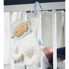A Kaloo brand musical plush sheep hanging in a crib as a mobile, with a baby looking up at it.