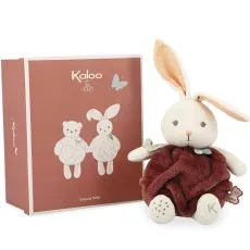 A soft Kaloo plush rabbit wearing a deep red fluffy wrap, standing next to a matching gift box