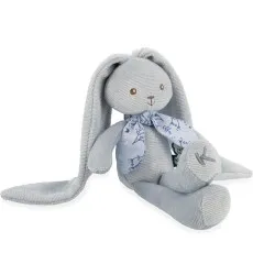 A stuffed gray rabbit with long floppy ears sits on a white surface with its legs crossed