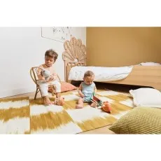 Two children playing with stuffed animals on a striped rug in a sunny bedroom.