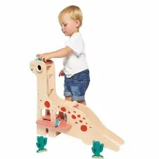 A young boy pushes a small dinosaur car down the ramp of a Janod wooden dinosaur toy.