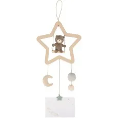 A plush teddy bear on a swing, hanging from a star-shaped wooden frame with a moon and pom-poms