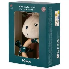 A white plush rabbit rattle with a wooden ring, packaged in a dark teal box with text and safety symbols