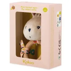 A side view of a plush white rabbit rattle toy inside a light pink package.