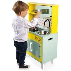 A child plays with a wooden toy kitchen set, which includes a microwave, stove, and sink..