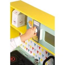 A child's hand turning the dial on the toy microwave of the Janod wooden play kitchen set.