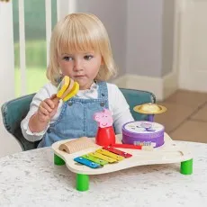 A young child with blonde hair playing with a Peppa Pig musical toy set.
