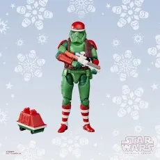 A Christmas-themed Stormtrooper action figure, holding a rifle, with a small red and green droid beside it.