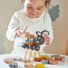 A toddler plays with a Janod balancing ant and colorful leaf-shaped pieces.