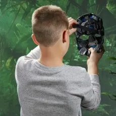 A young boy wearing a grey shirt with his back to the camera, holding up a Transformers Optimus Primal mask.