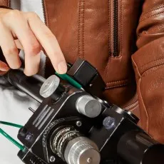 A close-up of a person's hand pressing a green button on a Ghostbusters Proton Pack wand