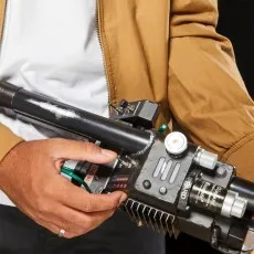 A person in a brown jacket holding a detailed replica of the Ghostbusters Proton Pack wand