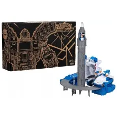 A boxed Transformers playset showing a gray rocket tower and a blue tank-like vehicle