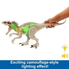 A hand holds a dinosaur toy with a glowing, green light on its torso and a wide-open mouth.