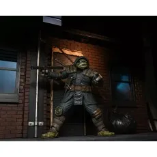 A hooded Ninja Turtle action figure with a staff, standing next to a garbage bag.