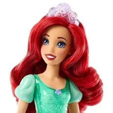 A close-up of a doll of Ariel with bright red hair, blue eyes, and a shiny silver tiara.