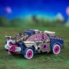 A Transformers Legacy Evolution Axlegrease toy in its vehicle mode, on a grassy, alien landscape.