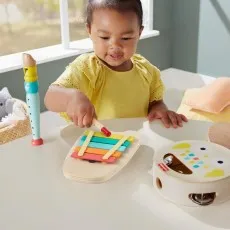 A child playing with a wooden xylophone and other musical toys