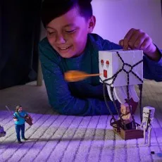 A boy playing on the floor with Minecraft figures, firing a projectile from a Ghast toy