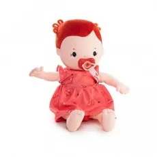 A close-up of a baby doll with orange hair, wearing a pink-red dress and holding a pacifier