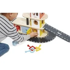 A child playing with a Janod wooden garage, using a key to open one of the doors.
