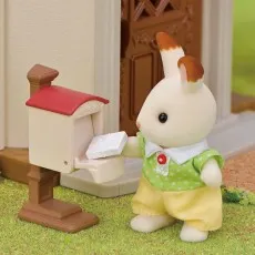 A Sylvanian Families rabbit figure is placing a white letter into a red-roofed mailbox
